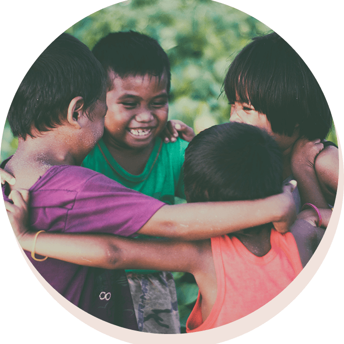 A group of children hugging each other in the grass.